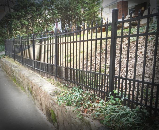 Metal fence with greenery and a house in the background