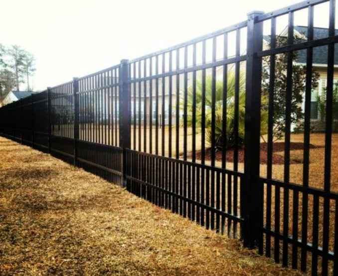 Black metal aluminum fence with a grassy area and trees in the background, designed for pets