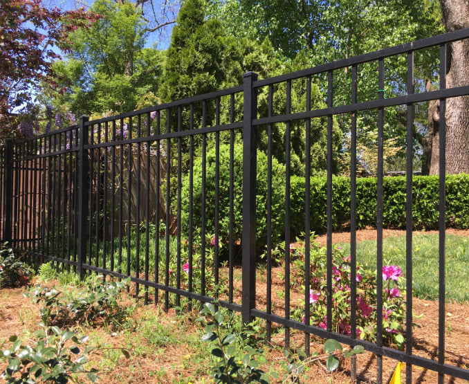 Aluminum black metal fence with greenery and flowers in a garden setting