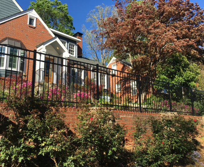 Aluminum black metal fence with smooth top and trees in the foreground