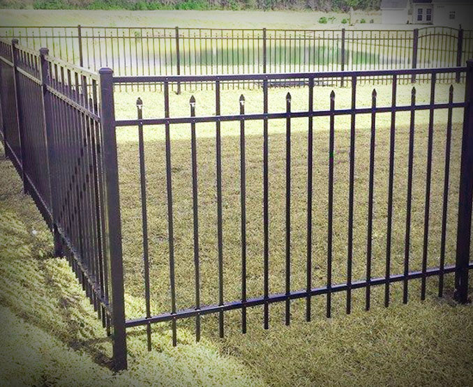 Black metal fence with decorative top rail on grassy area