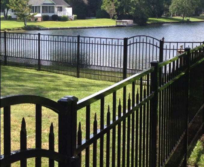Black metal aluminum fence with a scenic view of a lake and house in the background