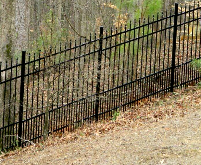 Black metal fence in a wooded area
