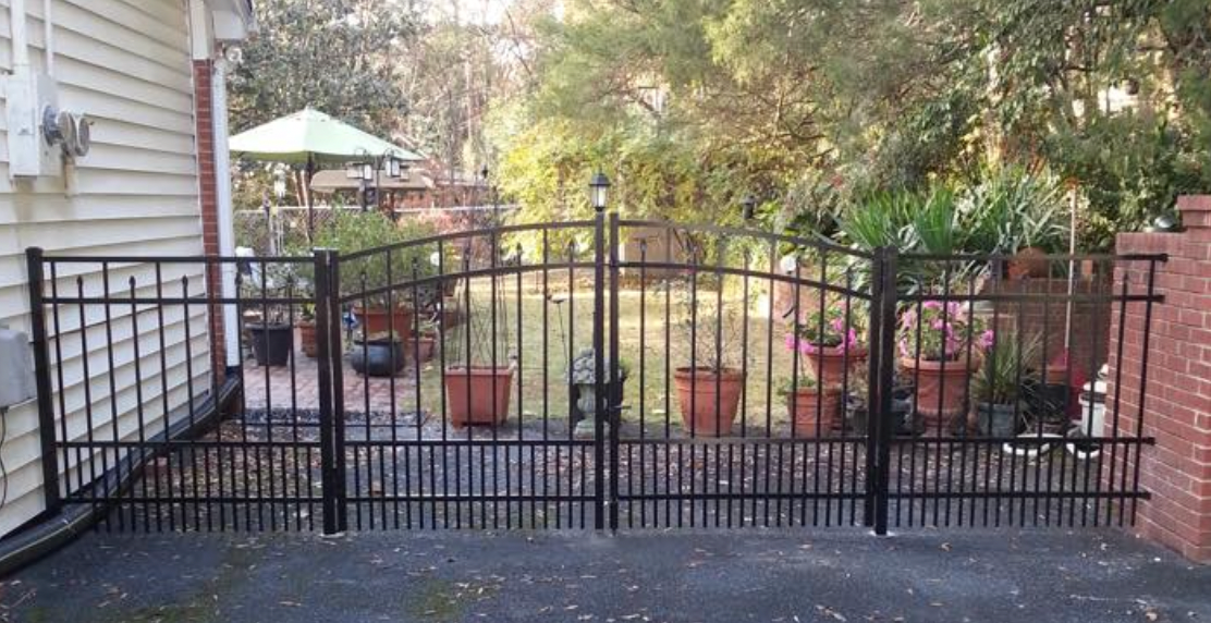 Black metal pet security fence with garden and house exterior in the background