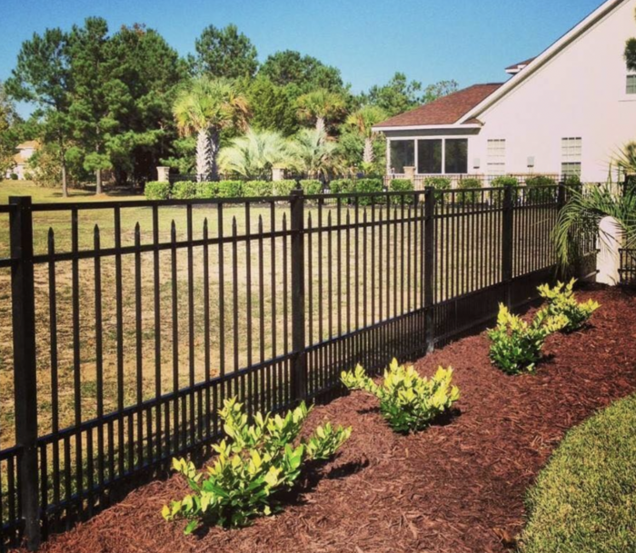 Black metal aluminum fence with greenery in a residential area