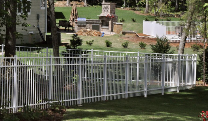 White metal fence in a backyard with a house and garden in the background