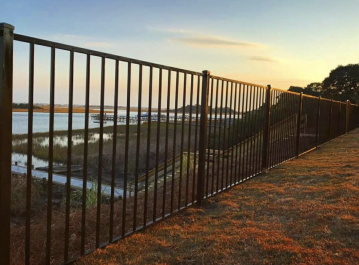 Metal fence 2-rail aluminum fence with a scenic view of a lake and dock at sunset.