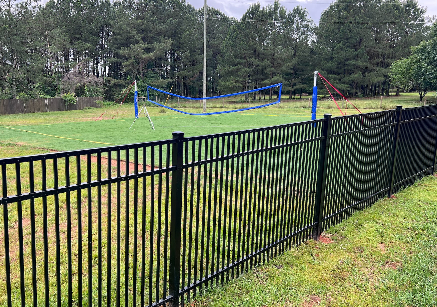 Black metal aluminum fence surrounding a sports field.
