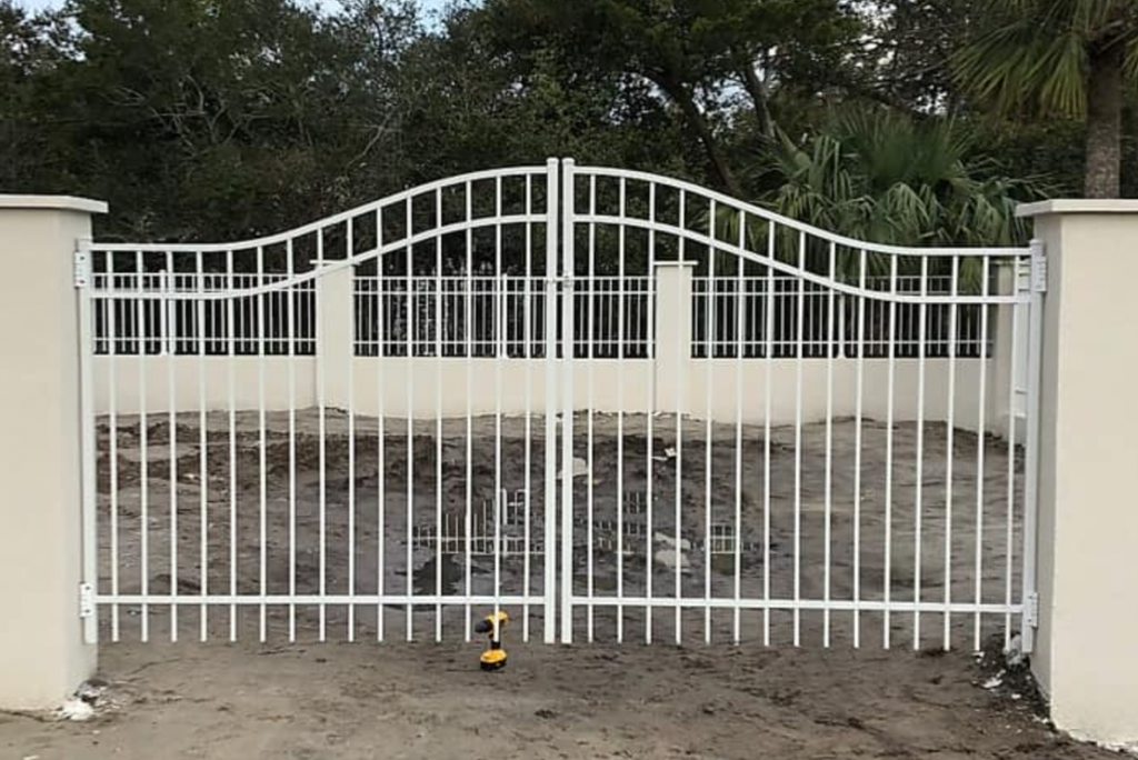 White metal aluminum driveway gate with decorative design in a natural setting